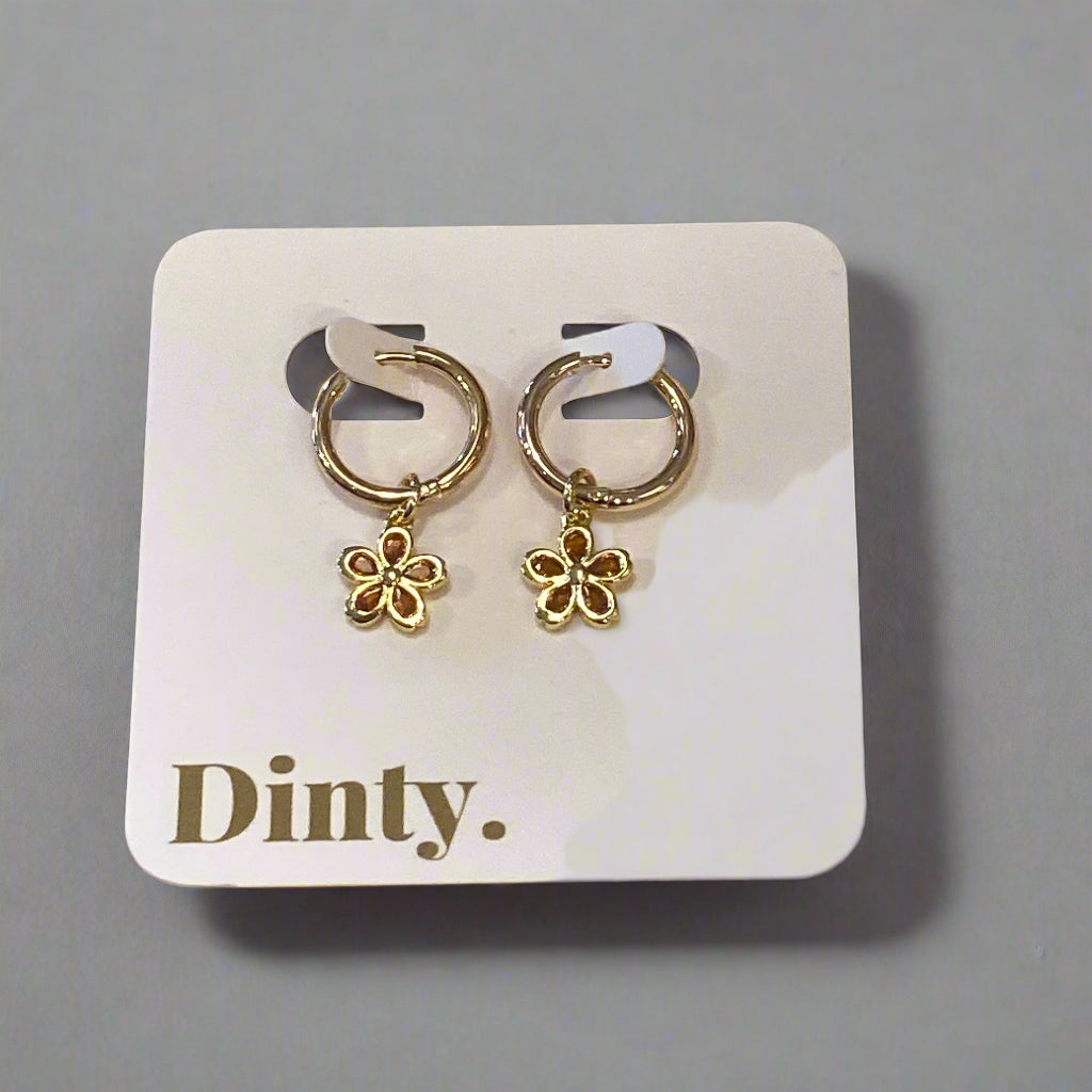 Gold hoop earrings on a 'Dinty.' branded card on a wooden surface