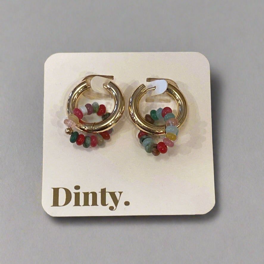 Gold hoop earrings with colorful beads on a Dinty branded card, placed on a wooden surface.