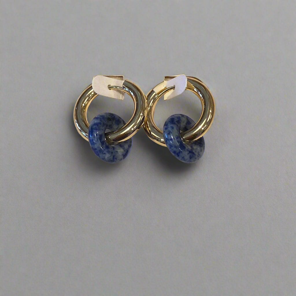 Pair of earrings on a Dinty branded card against a wooden background