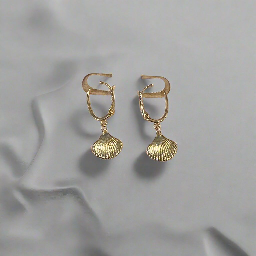 Gold earrings on a Dainty branded card against a wooden background