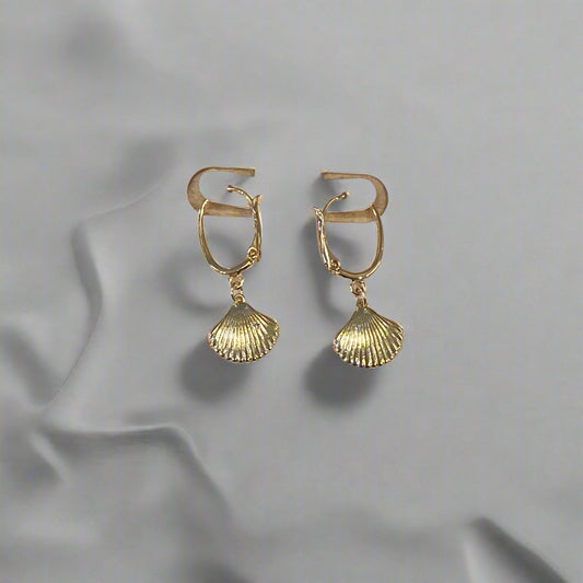 Gold earrings on a Dainty branded card against a wooden background