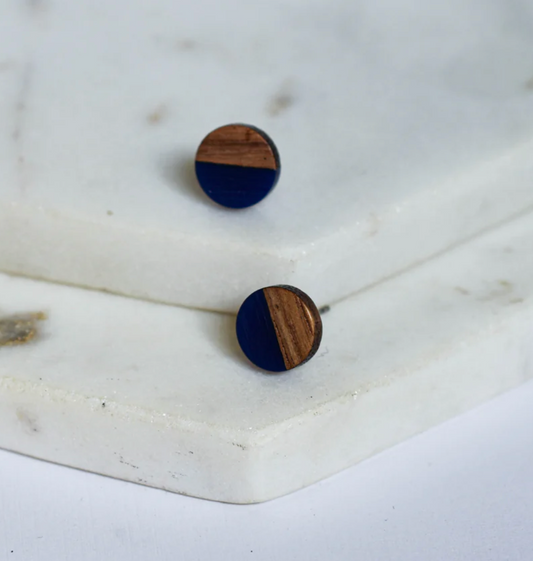 Wooden earrings with blue and brown design on a marble surface